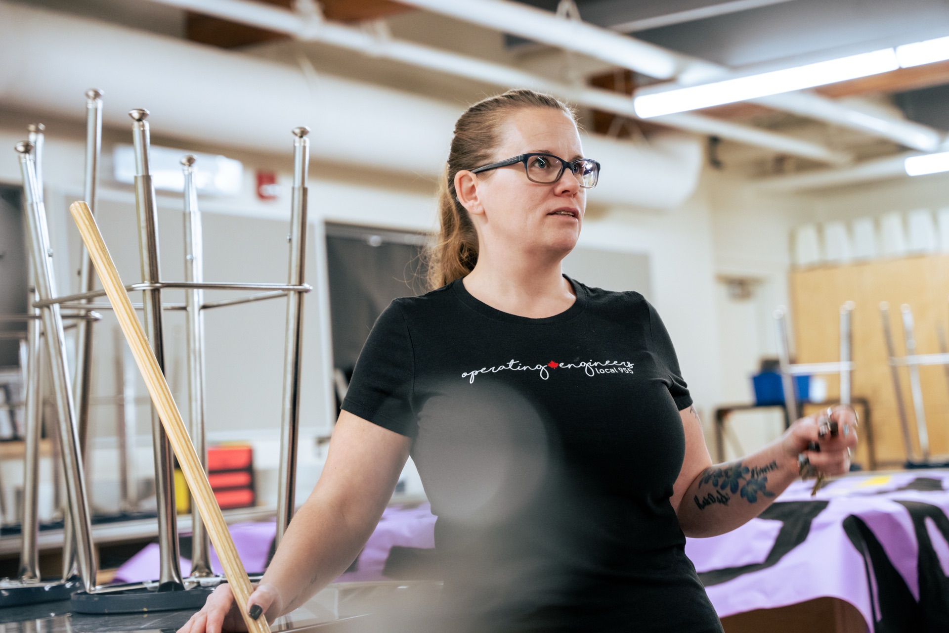 Woman wearing an Operating Engineers Local 955 T-shirt setting up an event hall