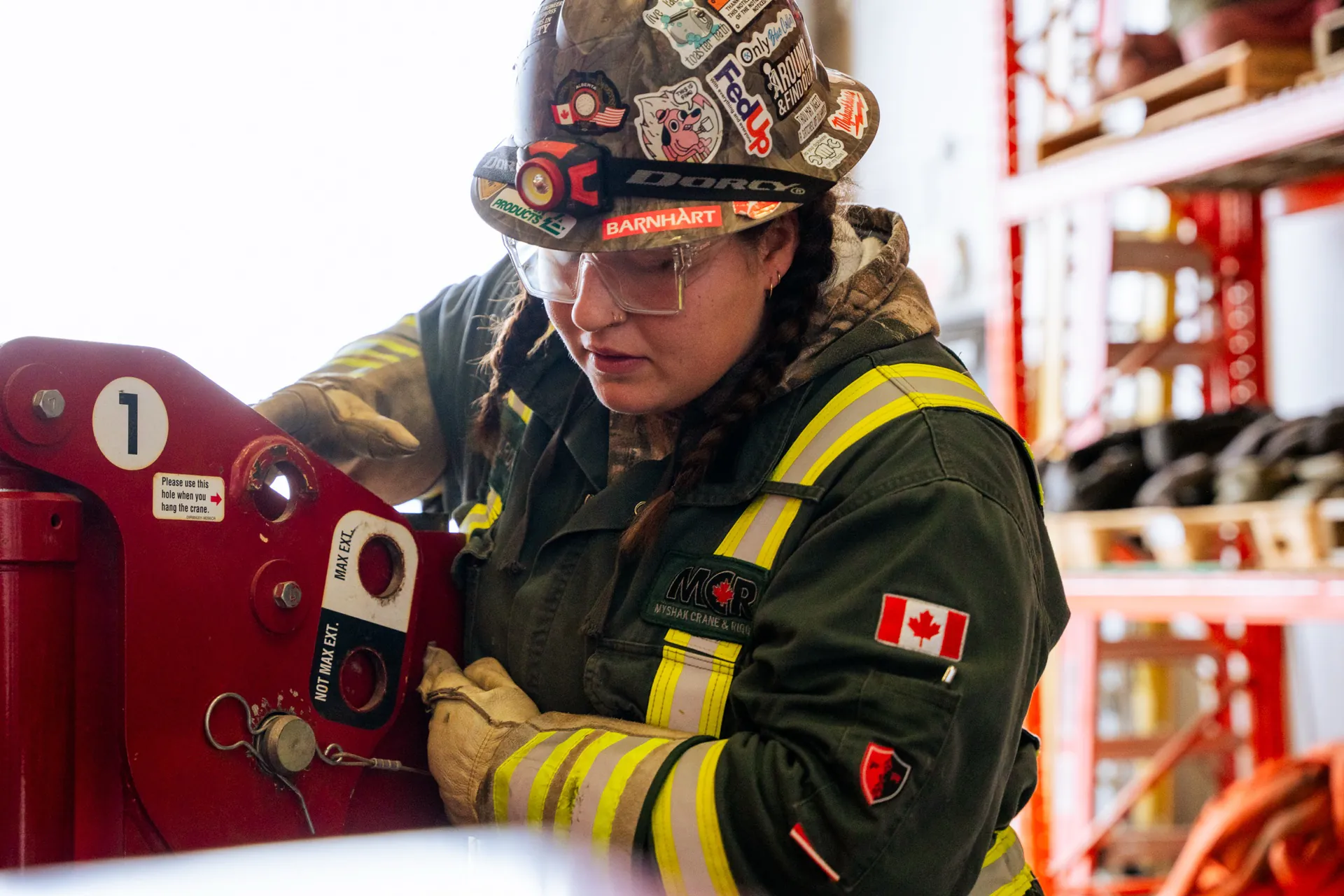 Woman crane rigger in Myshak Crane & Rigging gear working on a red crane component