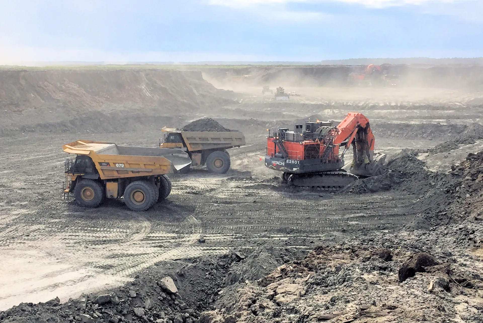 Hitachi hydraulic mining shovel loading Caterpillar haul trucks at an Alberta oil sands open pit mine
