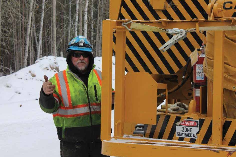 IUOE Local 955 operating engineer in hi-vis and hard hat giving a thumbs up beside a Caterpillar machine at a snowy jobsite
